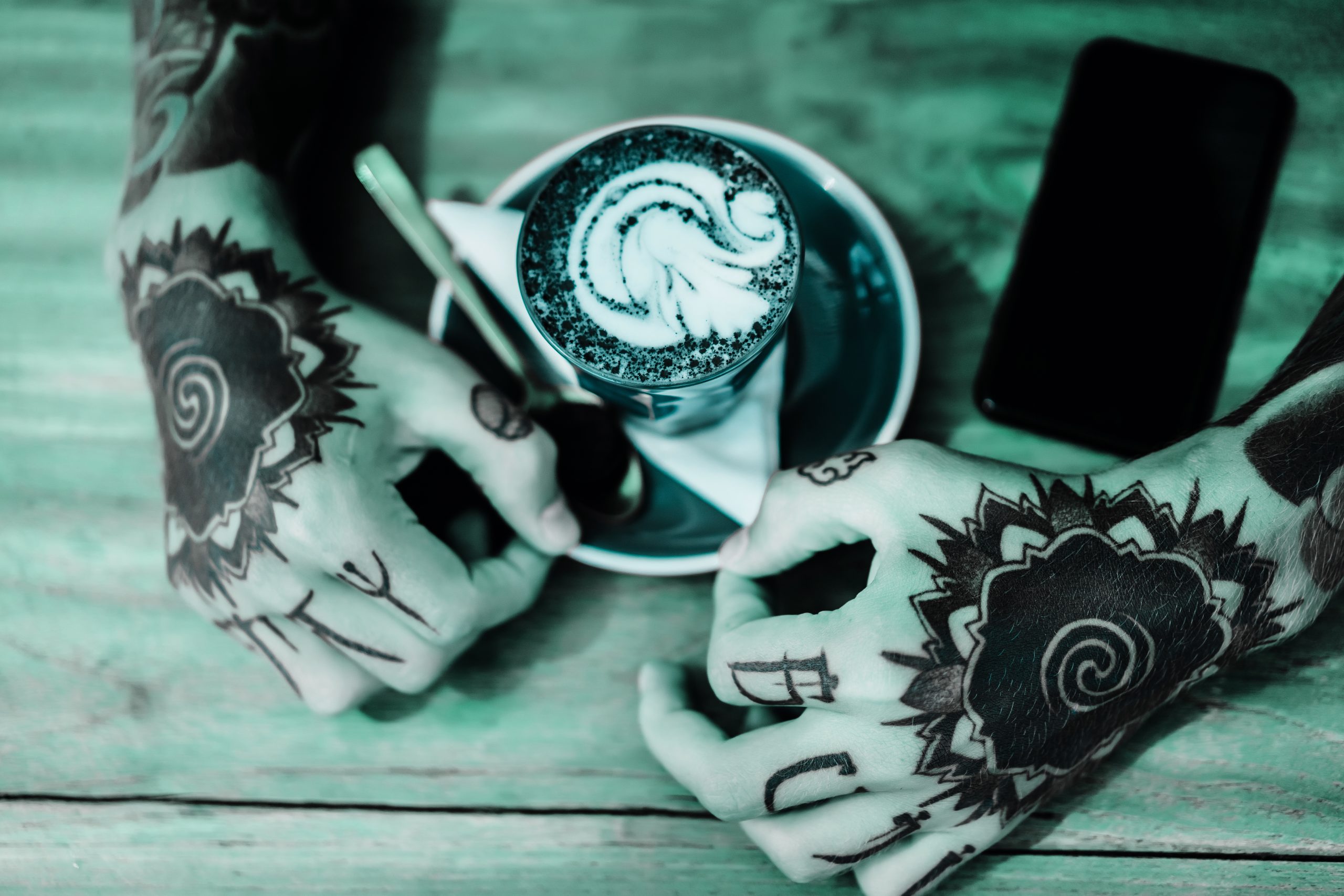 tattooed hands. hands holding a glass with coffee. smartphone